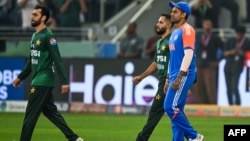 د هند د ۲۰ اووره کرکټ لوبډلمشر سوریاکمار یادو (ښي لوري ته) او ورڅخه مخکې پاکستانۍ لوبډلې کپتان سلمان علي اغا د سیالۍ لپاره لوبغالي ته داخلېږي - انځور له ارشیفه. 