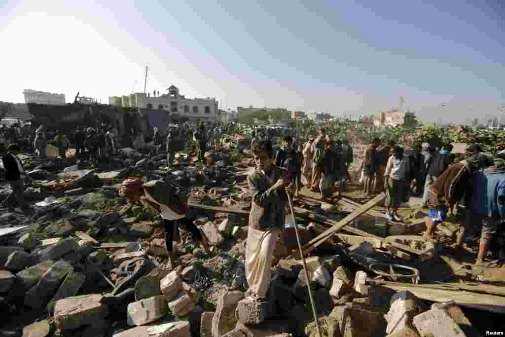 People gather at the site of an air strike on a residential area near Sanaa Airport in Yemen on March 26. (Reuters/​Khaled Abdullah)