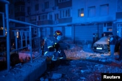 Спасатель отдыхает возле многоквартирного дома, поврежденного в результате атаки российского беспилотника. Киев, 30 мая 2023 года