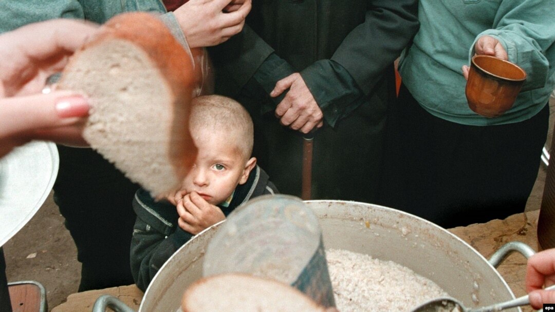 A boy stands among a line of people queuing for food at a charity distribution for poor people in Moscow.
