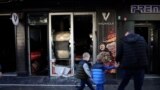People in Podgorica walk past a vandalized Turkish restaurant.