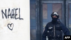 Një oficer policie franceze siguron hyrjen e një ndërtese teksa qëndron pranë emrit "Nahel''', i spërkatur në mur gjatë protestave në Nante, në Francën perëndimore më 30 qershor 2023.