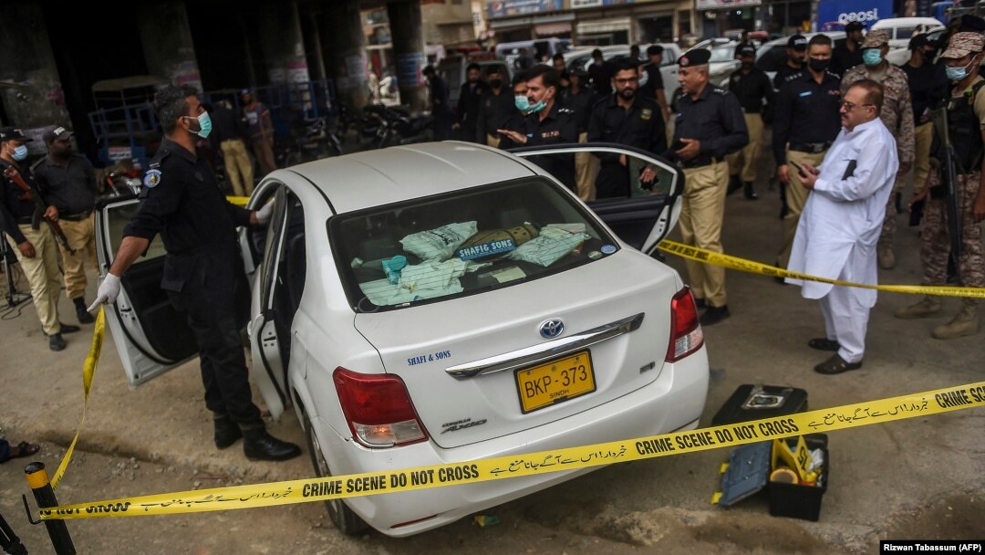 Security officials examine the car that was fired upon by gunmen in Karachi on July 28.