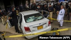 Security officials examine the car that was fired upon by gunmen in Karachi on July 28.