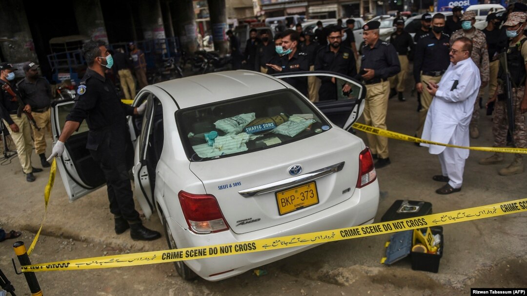 Investigators examine the scene where gunmen opened fire on two Chinese workers in Karachi on July 28. 