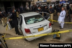 Security officials examine a car following a gun attack on the vehicle, which was carrying Chinese nationals in the Pakistani port city of Karachi in 2021.