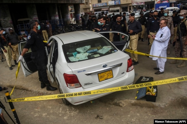 Security officials examine a car following a gun attack on the vehicle, which was carrying Chinese nationals in the Pakistani port city of Karachi in 2021.