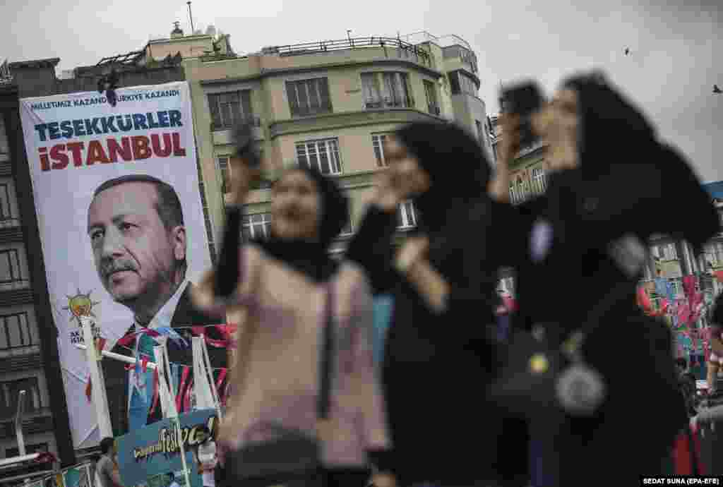 Turiștii musulmani pozează în fața unui poster al președintelui turc Recep Tayyip Erdogan, pe care scrie &bdquo;Vă mulțumim, Istanbul&rdquo; în Piața Taksim din Istanbul, pe 26 iunie, în aceeași zi în care Comisia Electorală Turcă a anunțat că Erdogan a câștigat alegerile prezidențiale din țară. Între timp, Partidul Justiției și Dezvoltării (AKP) a obținut 42,5% din voturi în alegerile parlamentare, însă a pierdut majoritatea absolută pe care a avut-o &nbsp;din anul 2002. (epa-EFE / Sedat Suna)