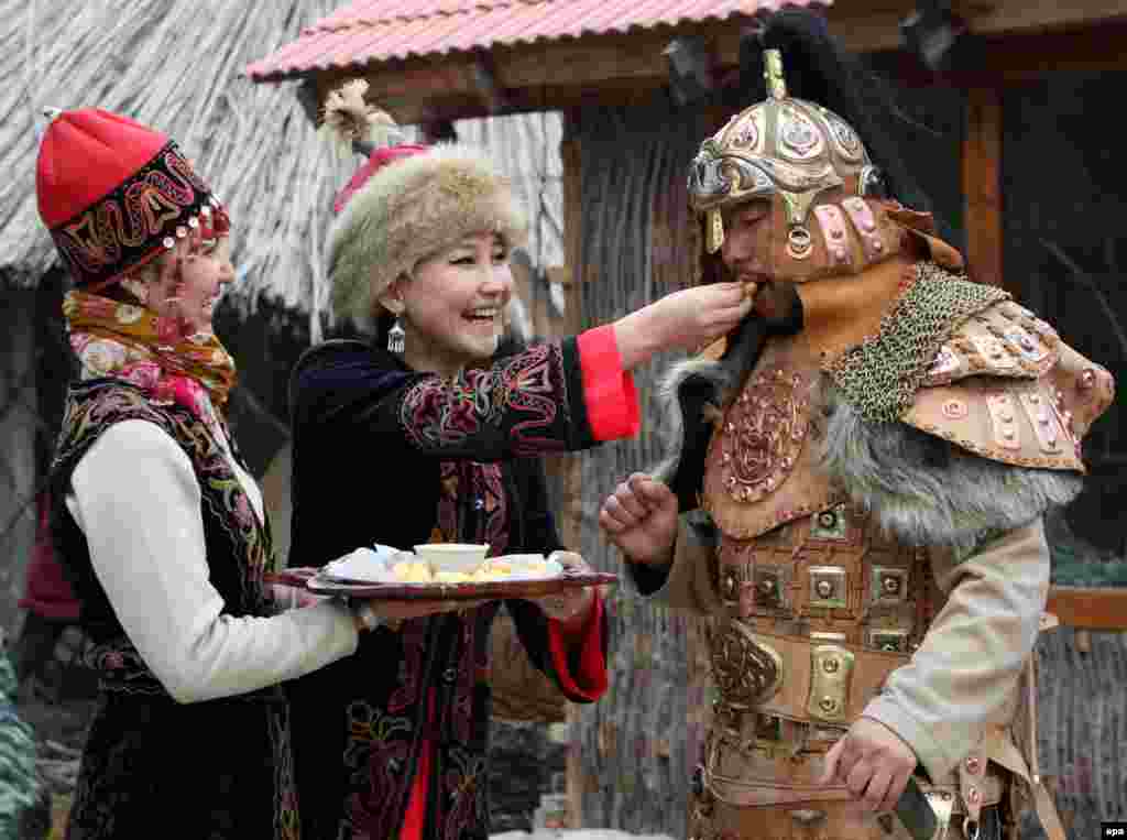 A woman dressed in national costume offers traditional local dishes during Norouz celebrations in Bishkek. (epa/Igor Kovalenko)