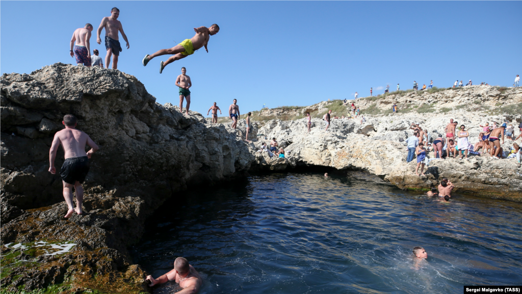 Отдыхающий прыгает в природный бассейн &laquo;Чаша любви&raquo; в Черном море на мысе Тарханкут, сентябрь 2021 года