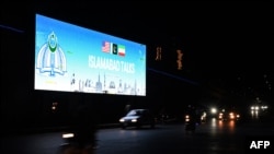 Commuters ride past a digital screen as the US and Iran hold peace talks in Islamabad on April 11-12.