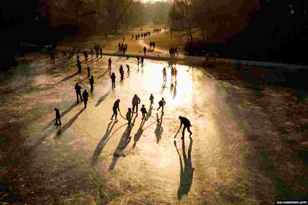 The sun sets as people play on a frozen pond and walk along the paths of a park in Berlin. (AFP/Odd Anderson)