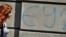 A woman walks past graffiti reading "EU?" in downtown Belgrade. (file photo)