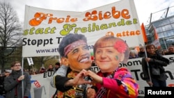 Protesters wearing masks depicting German Chancellor Angela Merkel and U.S. President Barack Obama demonstrate against Transatlantic Trade and Investment Partnership (TTIP) agreement ahead of Obama's visit to Hannover on April 23.