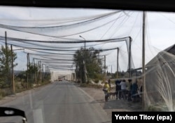 Netting covers a road near Konstantynivka, in eastern Ukraine, as locals queue at a shop on September 16