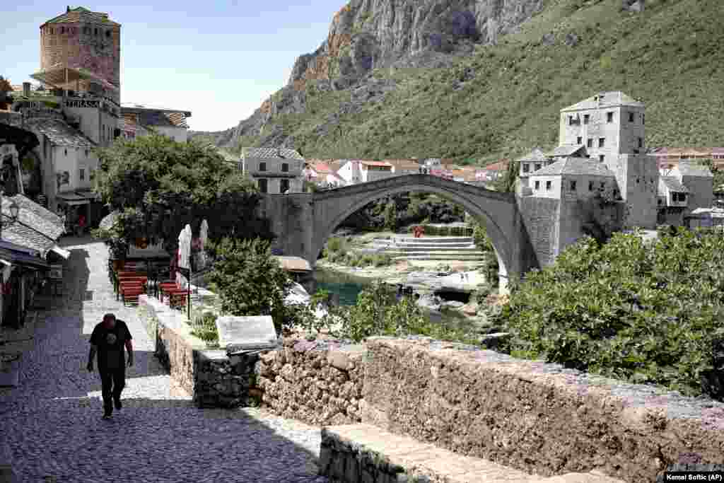 A man walks on a deserted street backdropped by the Old Bridge in Mostar, one of Bosnia&#39;s best-known landmarks. Hundreds of workers in Bosnia&#39;s tourism industry joined a protest against the government&#39;s ban on EU residents visiting the Balkan country, saying that thousands of them will lose their jobs unless the borders are open for EU citizens, as the industry cannot survive solely on visitors from Serbia, Croatia, or Montenegro.(AP/Kemal Softic)