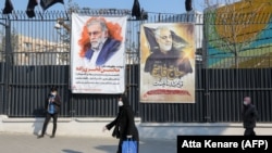 IRAN -- Iranians walk past a poster depicting late Revolutionary Guards commander Qasem Soleimani (R) and nuclear scientist Mohsen Fakhrizadeh, assassinated last month, in the capital Tehran, December 30, 2020