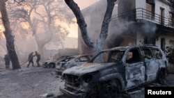 Pompierii muncesc la stingerea unui incendiu din suburbia Varympompi, la nord de Atena, Grecia, 3 august 2021.