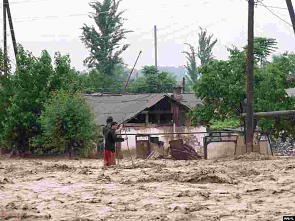 ...while men in the flooded Tajik village of Kulob resist being swept away. - Photo by RFE/RL