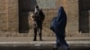Вооруженный сотрудник службы безопасности Афганистана и женщина в парандже. Афганский Герат. 20 июля 2021 года.