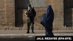 Вооруженный сотрудник службы безопасности Афганистана и женщина в парандже. Афганский Герат. 20 июля 2021 года.