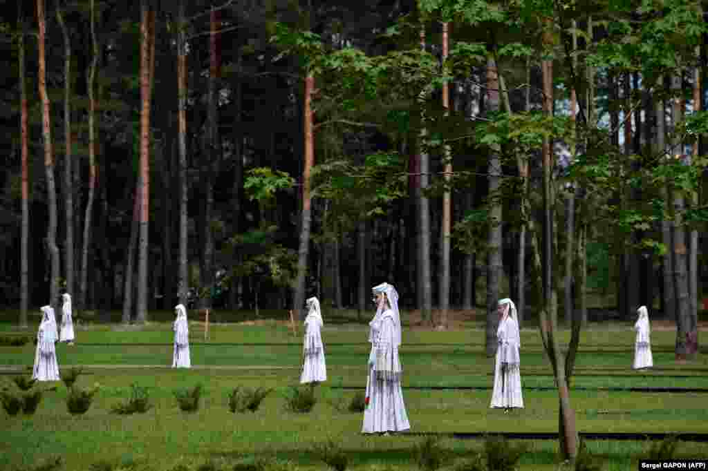 Artiștii participă la o ceremonie de dezvelire a unui monument consacrat victimelor celui de-al doilea război mondial, pe locul fostului lagăr de exterminare nazist Trostenets din Minsk, Belarus, pe 29 iunie. (AFP / Serghei Gapon)