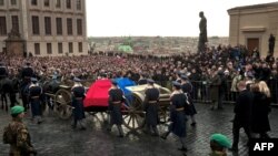 A caisson with the flag-draped coffin of former Czechoslovak dissident and Czech President Vaclav Havel arrives at Prague Castle on December 21, accompanied by his widow and surrounded by mourners.