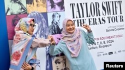 Fani ai lui Taylor Swift pozează la Stadionul Național din Singapore, pe 2 februarie, cu afișul șirului de concerte pe care le ține vedeta în orașul-stat din Asia de Sud-Est. 