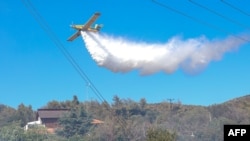 Un avion de pompieri pulverizează apă pentru a stinge un incendiu de vegetație în regiunea Ano Souli din Attica, Grecia. 12 august 2024.