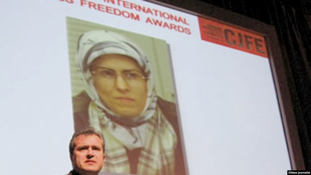 An image of Zhila Baniyaghoub flanks a presenter at an International Press Freedom Award event in Toronto in December 2009.