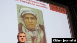 An image of Zhila Baniyaghoub flanks a presenter at an International Press Freedom Award event in Toronto in December 2009.