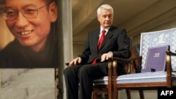 Голова Норвезького Нобелівського комітету Торбйорн Яґланд дивиться на сертифікат про вручення Нобелівської премії миру і медаль на порожньому кріслі, де мав би сидіти Лю Сяобо. Портрет останнього висить на стіні під час церемонії нагородження в Осло, 10 грудня 2010 року