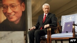 The chairman of the Nobel Committee, Thorbjoern Jagland, looks down at the vacant chair of Nobel Laureate Liu Xiaobo (pictured at left), on which Jagland placed the Nobel Peace Prize diploma and gold medal.