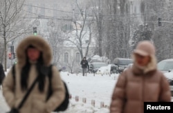Residents walk on a snow-covered street in Kyiv, where power and heating infrastructure have been badly damaged by Russian attacks, on January 15.