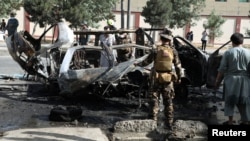 Afghan security forces inspect the wreckage of a passenger van after a bombing in Kabul on June 12.