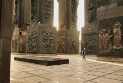 Чоловік проходить через колони пам'ятника «Хроніка Грузії»