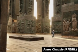 A man walks through the pillars of the Chronicle of Georgia monument.