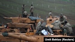 Turkish soldiers stand on top of their tanks near the Turkish-Syrian border in Hatay province, Turkey January 24, 2018