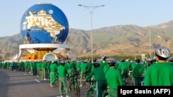 Biciklisti se okupljaju ispred 30-metarskog spomenika biciklizmu, koji je postao važna komponenta državne propagande koja promoviše zdrav životni stil, u Ašgabatu, juni 2020.