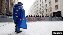 Ýewropa Bileleşiginiň baýdagyna bürenen demonstrant. Kiýew.