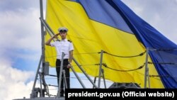 Матрос ВМС на тлі величезного прапора України на фрегаті «Гетьман Сагайдачний» під час навчань «Сі бриз-2018». Одеса, 16 липня 2018 року