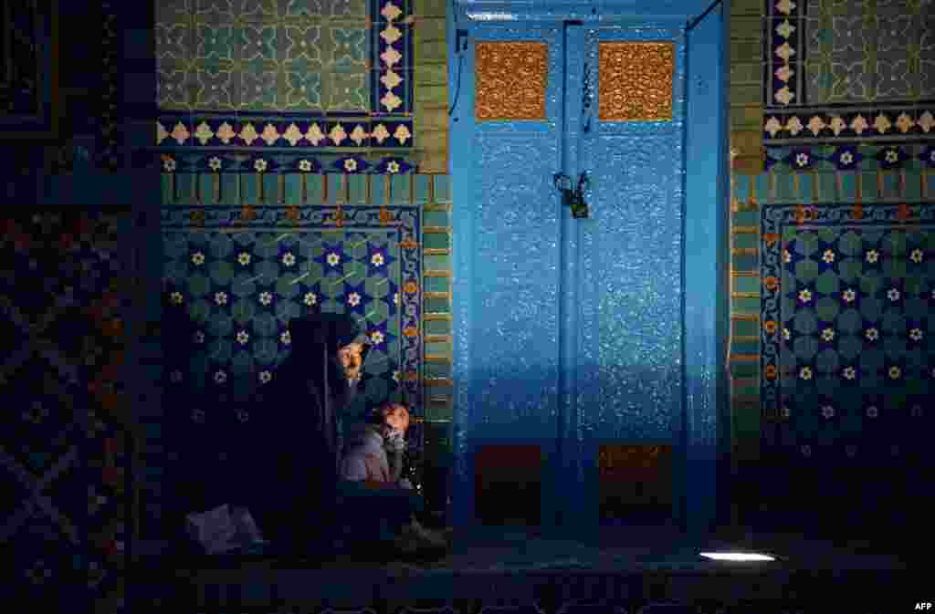 An Afghan burqa-clad woman waits to break fast during the holy month of Ramadan at the Hazrat-e Ali shrine, or Blue Mosque, in Mazar-e Sharif on June 30. (AFP/Farshad Usyan)