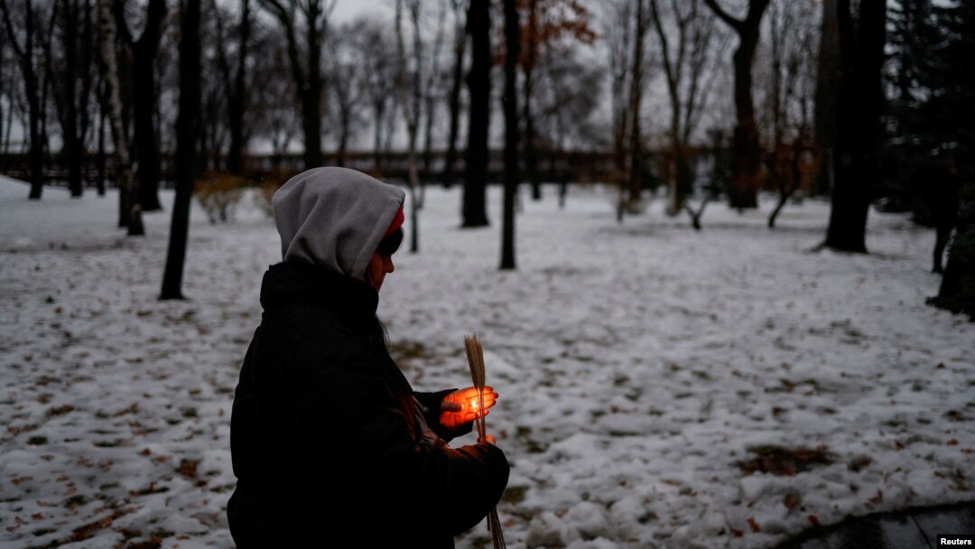 Момче пали свещ пред паметника на жертвите на Голодомора в снежен Киев на 26 ноември.