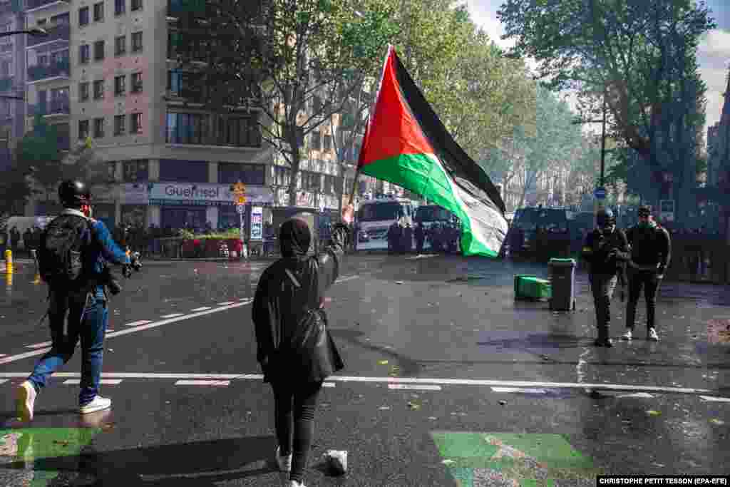 O femeie agită un steag palestinian în timpul ciocnirilor protestatarilor cu poliția, în timpul unui miting organizat de mai multe asociații în sprijinul poporului palestinian, la Paris, Franța, 15 mai 2021.