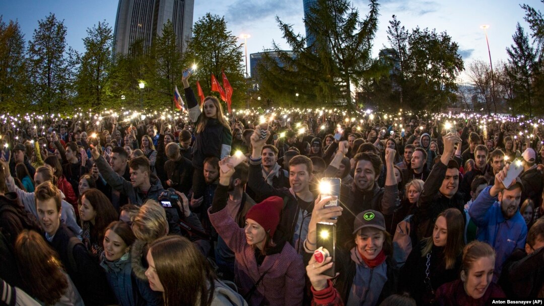 Demonstrators wave their phones as they gather in front of a newly built fence blocked by police during a protest against plans to construct a church in a park in Yekaterinburg on May 15.