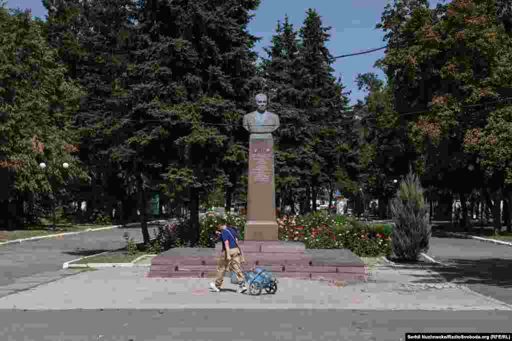 Një adoleshent tërheq një karrocë të vogël me bidonë me ujë pranë një monumenti të një Heroi të Bashkimit Sovjetik, Kirill Moskalenko, i cili ka lindur aty pranë.