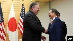 U.S. Secretary of State Mike Pompeo, left, and Japan's Chief Cabinet Secretary Yoshihide Suga shake hands at Prime Minister's office in Tokyo Saturday, Oct. 6, 2018. Pompeo has arrived in Tokyo for talks with Japanese officials ahead of his trip to North 