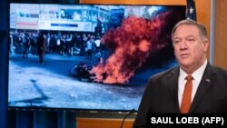 US Secretary of State Mike Pompeo speaks alongside a photograph of demonstrations in Iran as he holds a press conference at the State Department in Washington, DC, November 26, 2019.