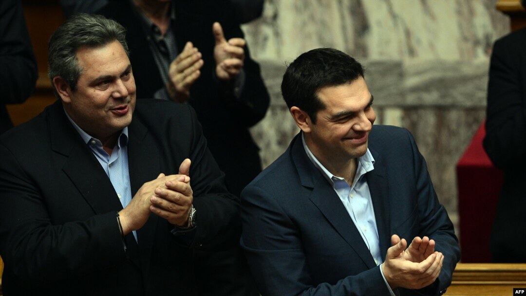Greek Prime Minister Alexis Tsipras (right) and member of coalition government and Defense Minister Panos Kammenos applaud as the government wins a confidence vote early on February 11.