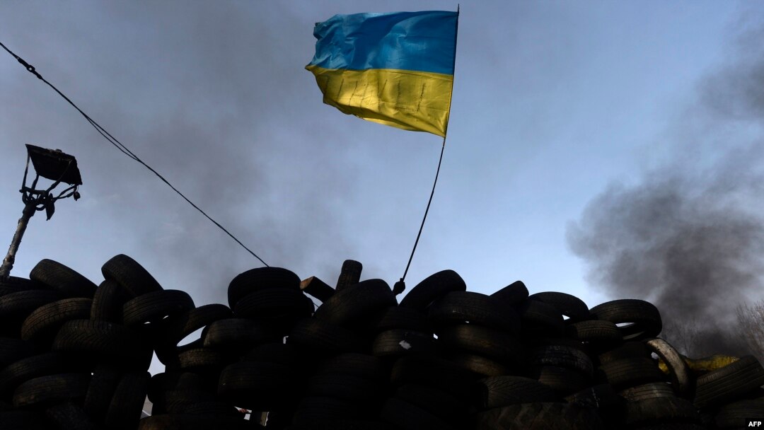 An antigovernment protester waves a Ukrainian flag behind a roadblock in Kyiv on January 27.